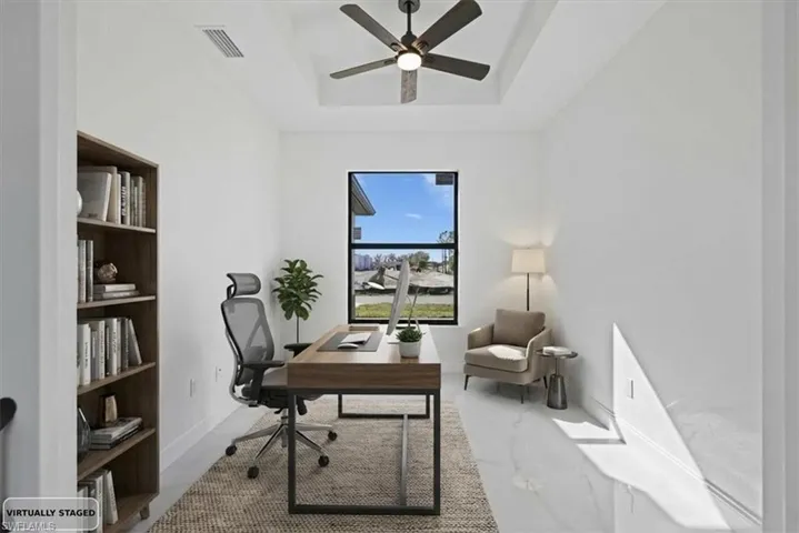 Photo Staged. Home office featuring a raised ceiling and ceiling fan