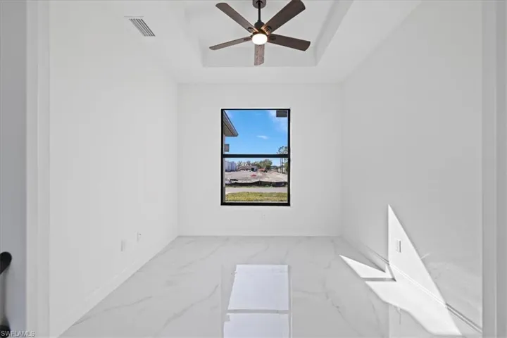 Spare room featuring ceramic flooring, a raised ceiling, and a ceiling fan