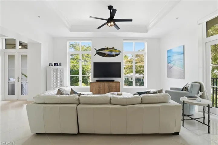 Living room with a ceiling fan, light tile patterned floors, and french doors