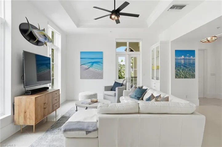 Living room with ceiling fan, light tile patterned flooring, and crown molding