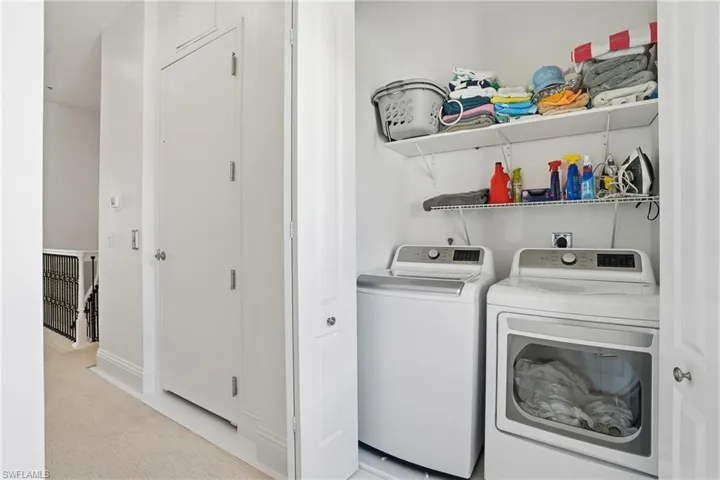 Laundry area featuring light colored carpet and separate washer and dryer