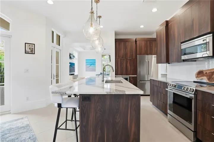 Kitchen featuring stainless steel appliances, modern cabinets, a kitchen breakfast bar, backsplash, and a center island with sink