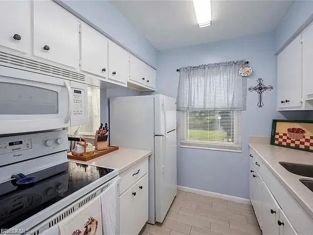 Kitchen featuring white appliances, white cabinets, and light countertops