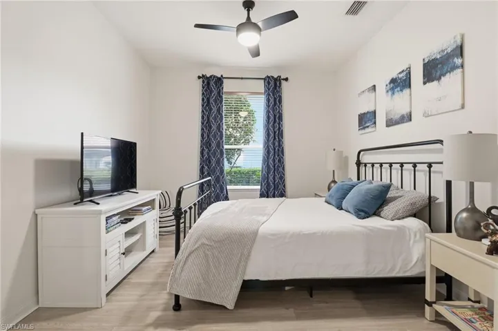 Den converted to a bedroom with light wood-type flooring and ceiling fan- Queen bed
