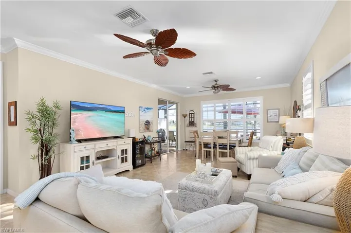 Tiled living room featuring ceiling fan and crown molding