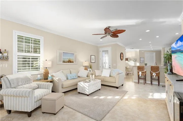 Living room with light tile patterned flooring, crown molding, ceiling fan, and a healthy amount of sunlight
