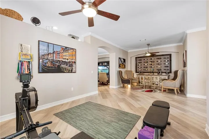 Workout room featuring ornamental molding, ceiling fan, and light wood-type flooring
