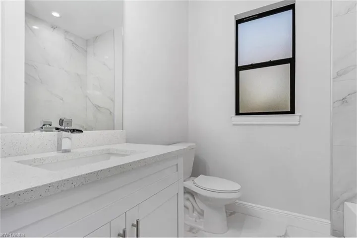Bathroom featuring light marble finish floors, vanity, and recessed lighting
