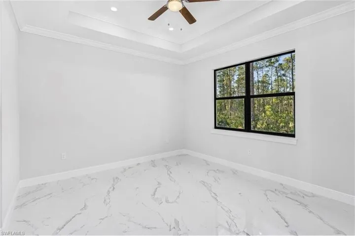 Empty room featuring a raised ceiling, crown molding, marble finish flooring, a ceiling fan, and recessed lighting