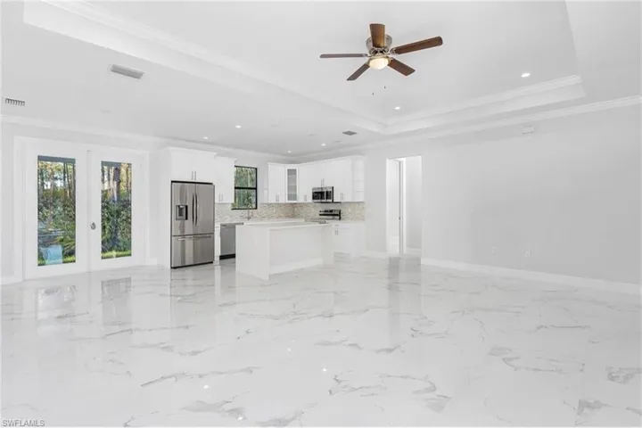 Unfurnished living room featuring ornamental molding, french doors, light marble finish floors, recessed lighting, and ceiling fan