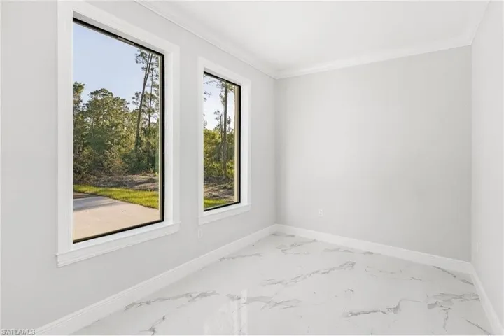 Spare room with light marble finish floors and crown molding