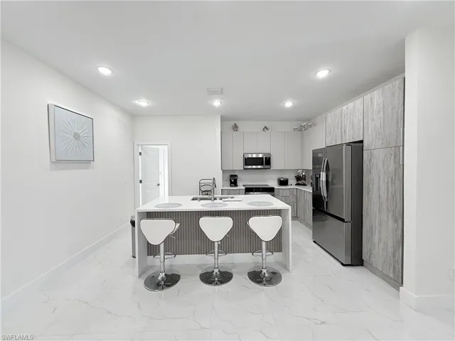 Kitchen featuring a breakfast bar area, sink, a center island with sink, and appliances with stainless steel finishes