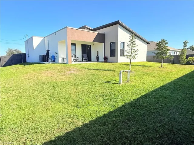 Rear view of property featuring cooling unit, a patio area, and a yard