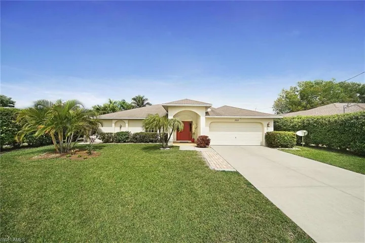 View of front of property featuring a garage, stucco siding, driveway, and a front lawn