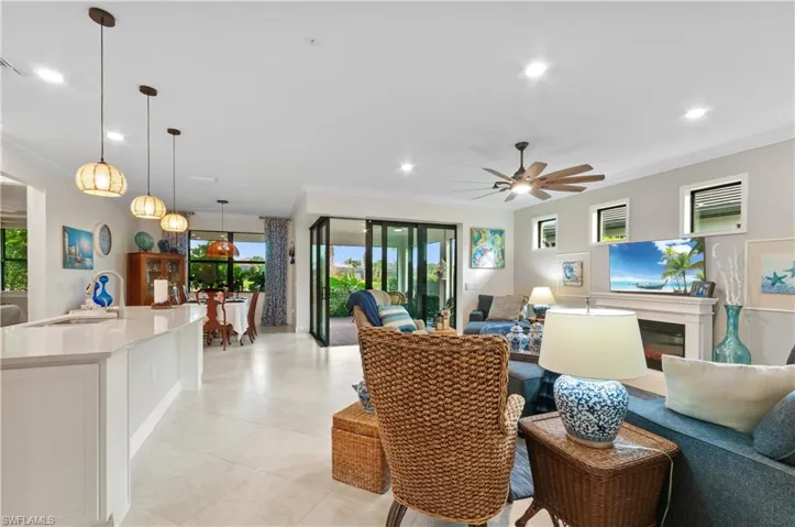 Living area with crown molding, healthy amount of natural light, a glass covered fireplace, recessed lighting, and ceiling fan