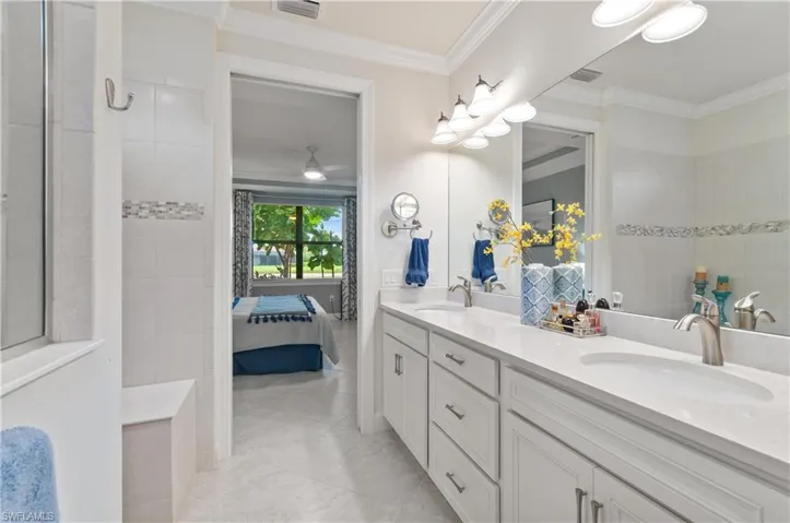 Bathroom featuring connected bathroom, double vanity, crown molding, a walk in shower, and ceiling fan