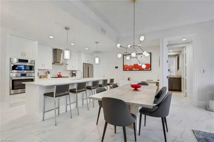 Dining room featuring hanging lights and light marble finish floors
