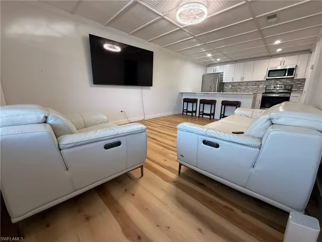 Living room with light wood-style flooring and recessed lighting