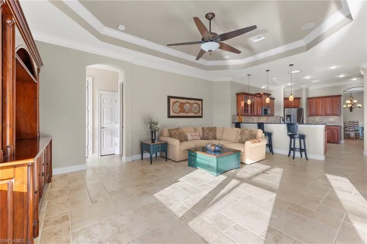 Living room featuring crown molding, ceiling fan with light and slider to pool.