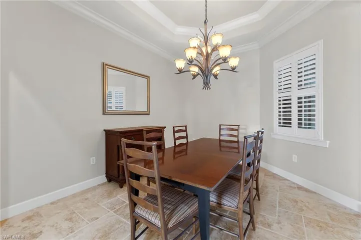 Tiled dining area featuring Plantation shutters, crown molding and tray ceiling