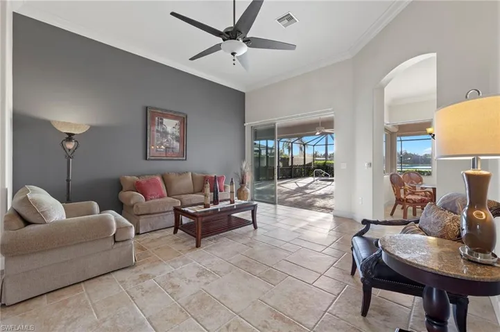 Living room with ceiling fan, crown molding, and light tile flooring