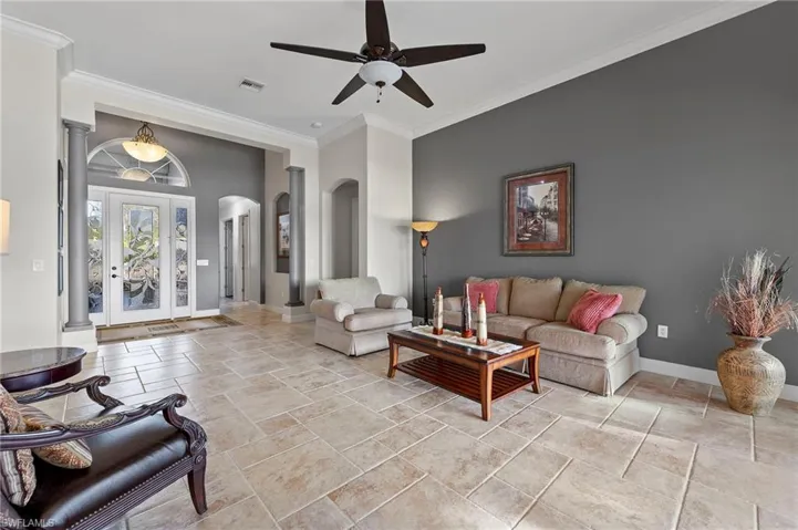 Tiled living room with crown molding and ceiling fan