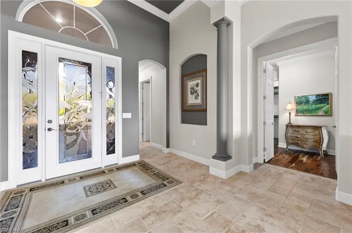Tiled entryway featuring decorative columns and crown molding