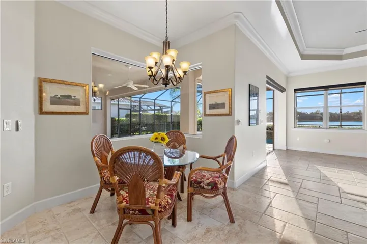 Dining space with chandelier, crown molding, a wealth of natural light, and light tile floors
