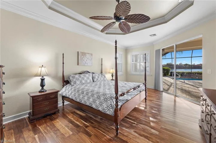 Bedroom featuring a tray ceiling, access to lanai, ceiling fan, and  hardwood / wood-style flooring