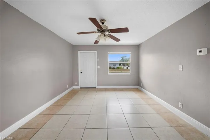 Empty room with a ceiling fan, light tile patterned floors, and a textured ceiling