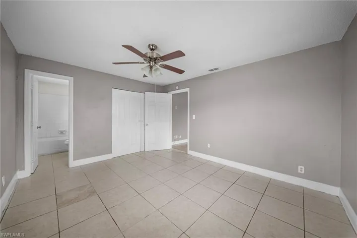 Unfurnished bedroom featuring a closet, light tile patterned flooring, ceiling fan, and ensuite bathroom