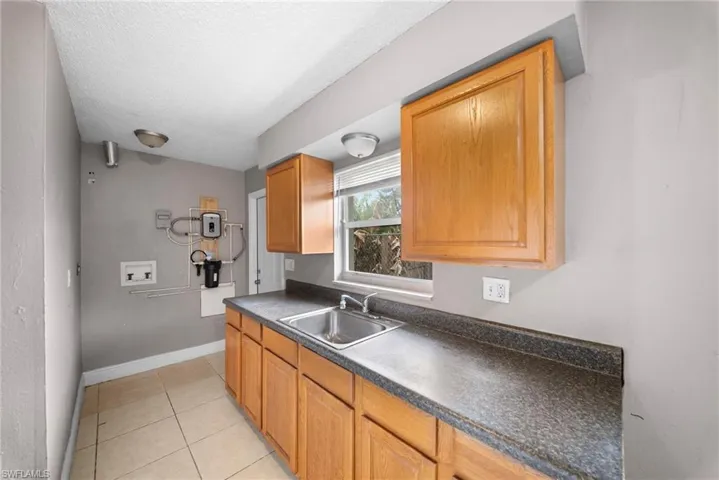 Kitchen featuring dark countertops, light tile patterned flooring, a textured ceiling, and wood finish cabinets