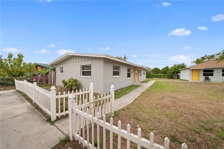 View of side of property featuring a fenced front yard and stucco siding