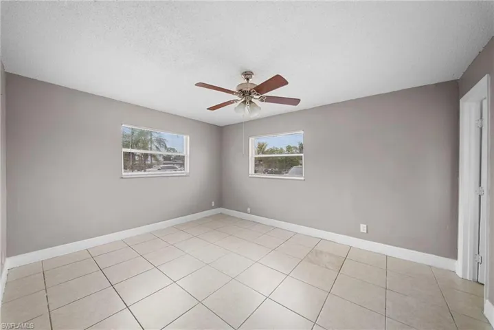 Unfurnished room featuring a textured ceiling, healthy amount of natural light, ceiling fan, and light tile patterned floors