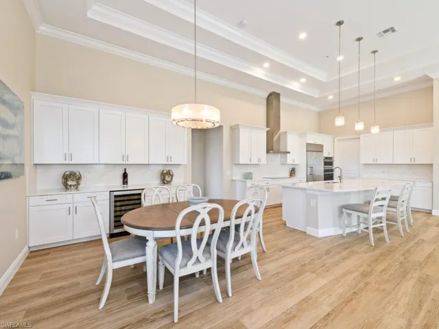 Dining room featuring ornamental molding, beverage cooler, a tray ceiling, and light / wood-style tile floors