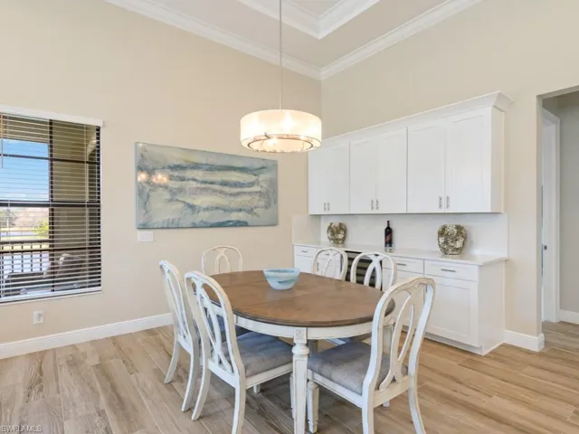 Dining room with light hardwood / wood-style tile floors and crown molding