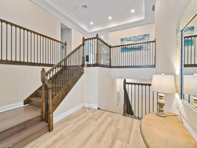 Stairway with wood-type tile, a raised ceiling, and crown molding