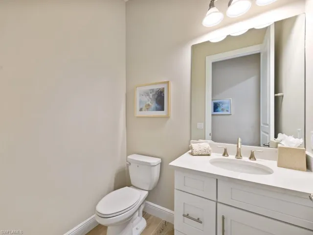 Powderoom featuring toilet, vanity, and wood-style tile floors