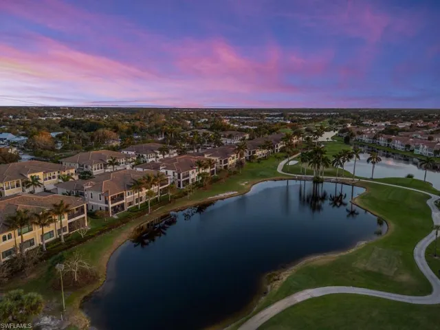 Aerial view at dusk featuring a water and golf course view