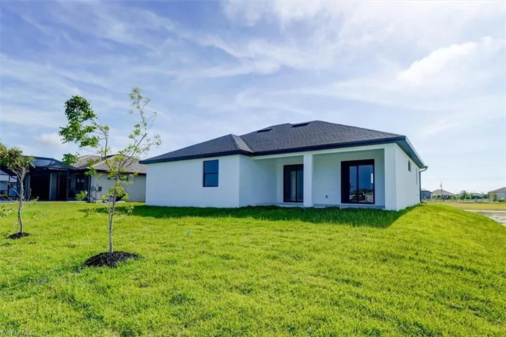Back of property featuring stucco siding, a patio, and a lawn