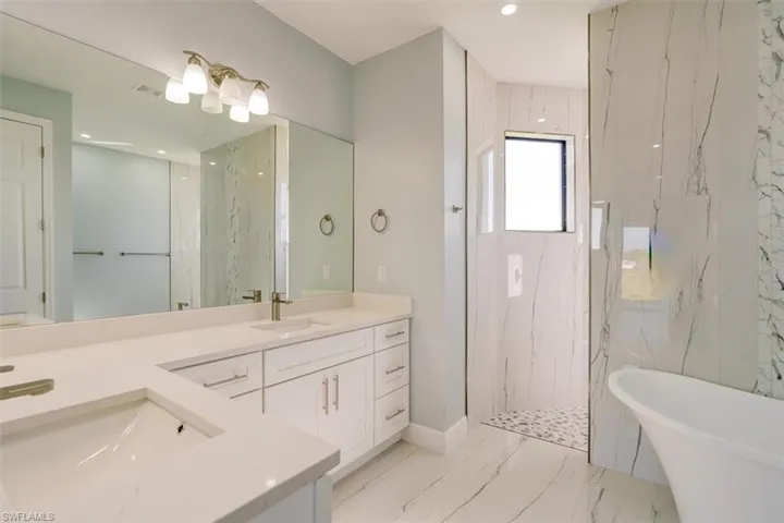 Full bath featuring a marble finish shower, double vanity, a freestanding tub, recessed lighting, and light marble finish floors