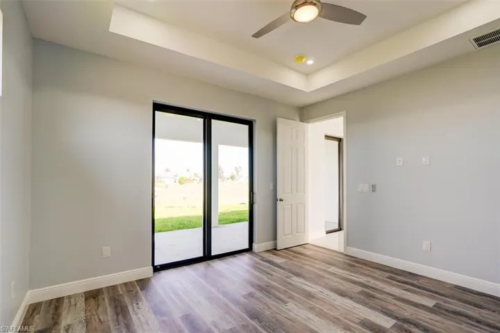 Empty room featuring a raised ceiling, wood finished floors, recessed lighting, and ceiling fan