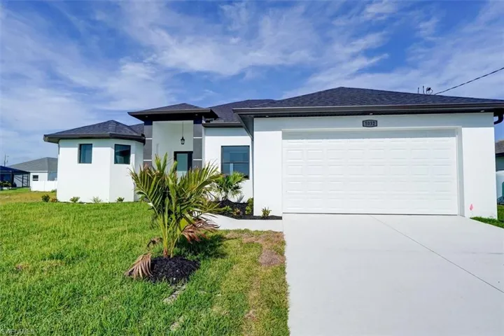 Coastal modern house featuring stucco siding, concrete driveway, an attached garage, and a front yard