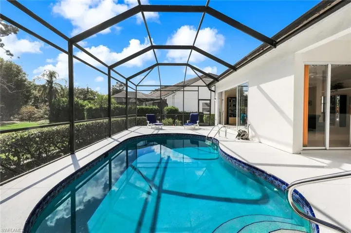 Swimming pool featuring a sunroom, a patio area, and glass enclosure