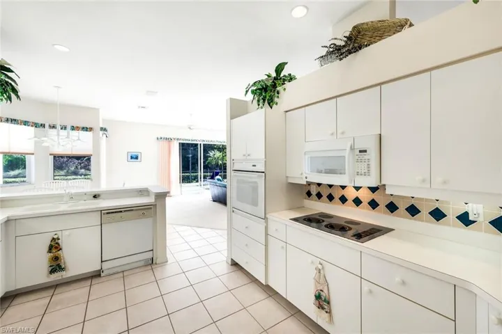 Kitchen featuring light countertops, white appliances, white cabinetry, and healthy amount of natural light