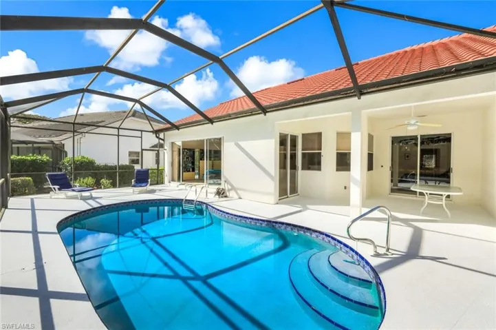 Swimming pool with a sunroom, a patio area, and glass enclosure