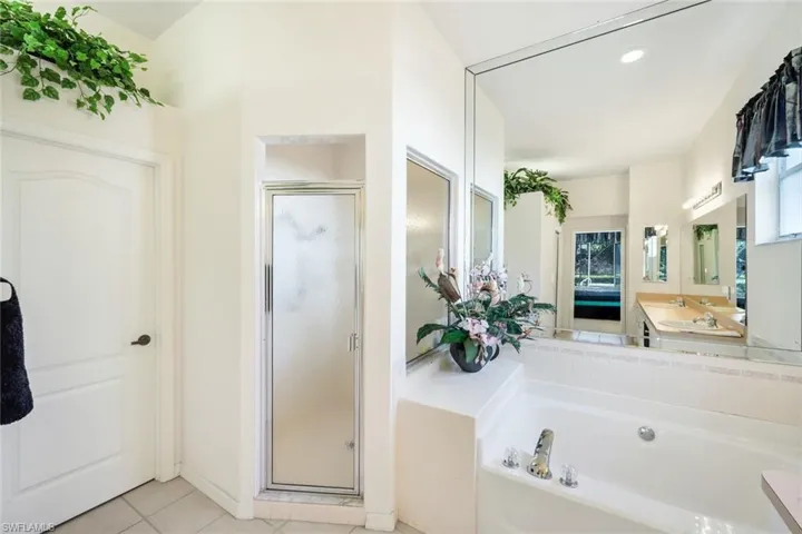 Ensuite bathroom featuring a garden tub, a stall shower, light tile patterned floors, vanity, and recessed lighting