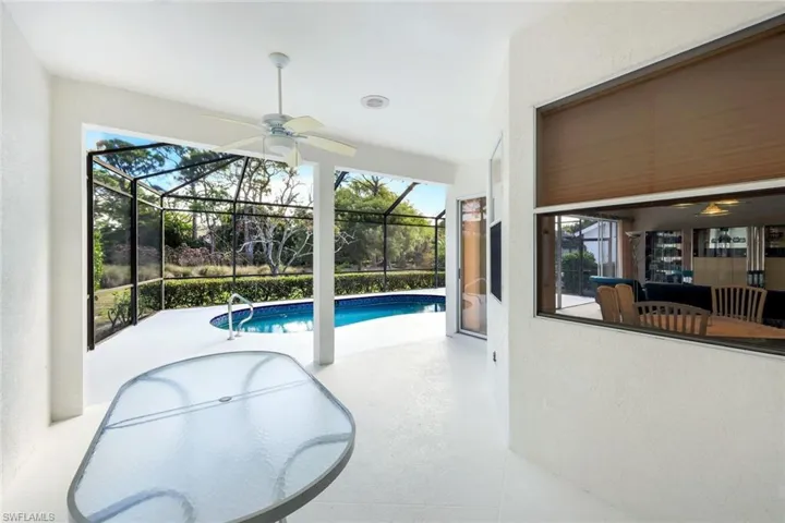Swimming pool featuring a sunroom, a patio, and glass enclosure