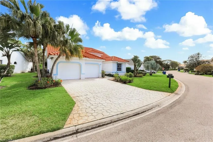 Mediterranean / spanish-style house featuring a front yard, a tile roof, stucco siding, decorative driveway, and an attached garage