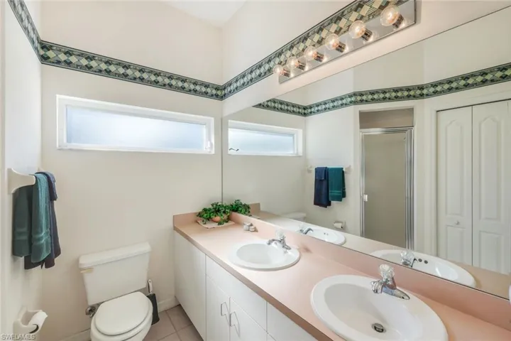 Full bath with double vanity, a stall shower, a closet, and light tile patterned floors